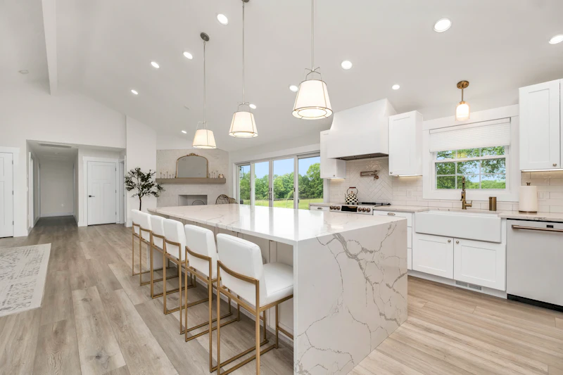 Bright kitchen with a marble waterfall island and brass stools