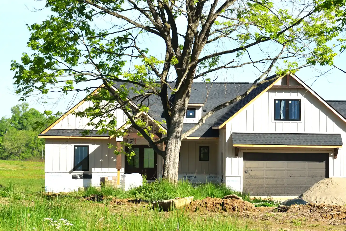 Newly built farmhouse with fresh grading and a dirt pile in the yard
