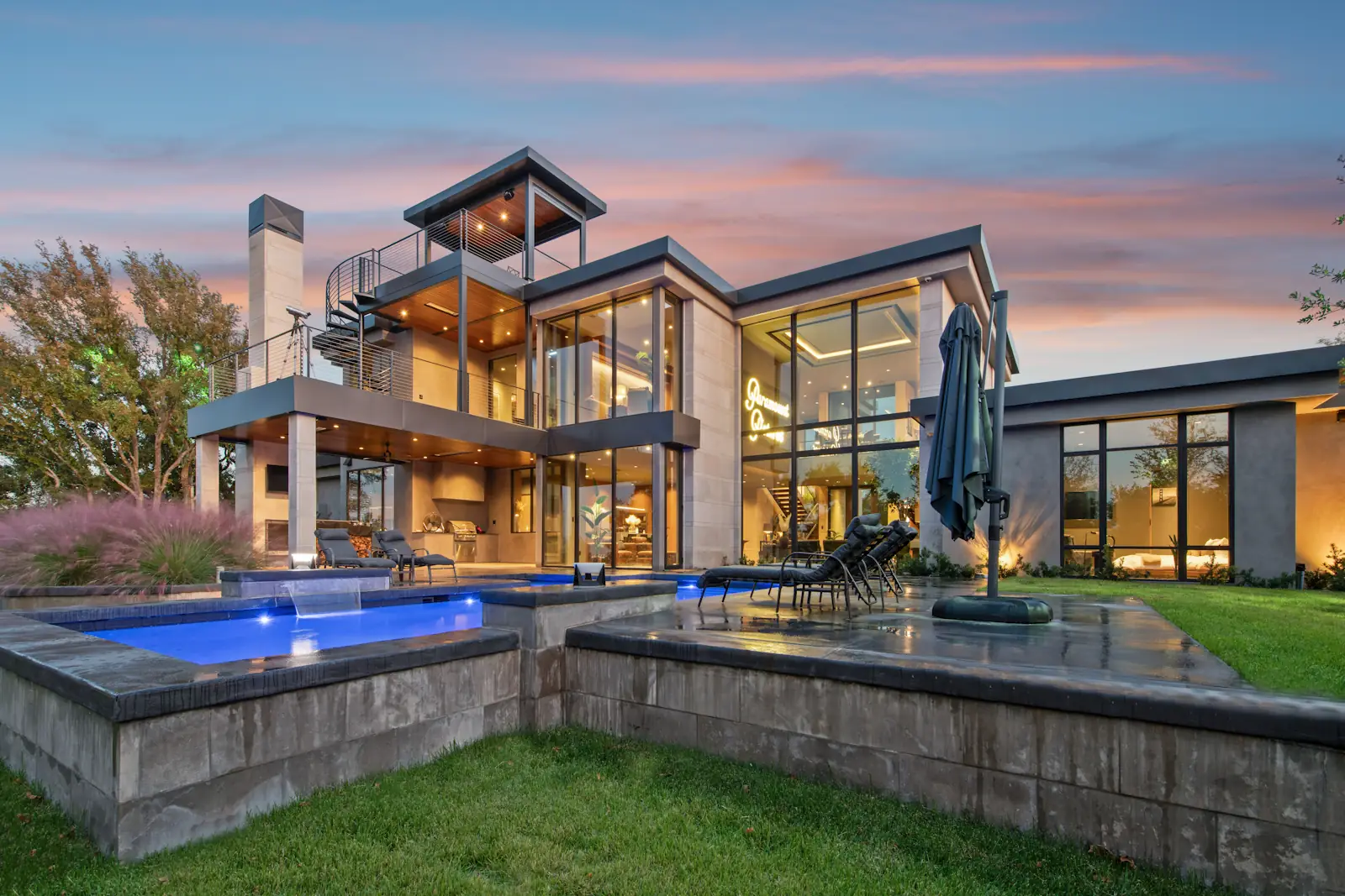 Modern home with a pool and outdoor living area at dusk
