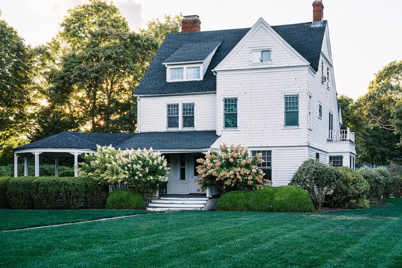 Traditional two-story shingle house with hydrangeas
